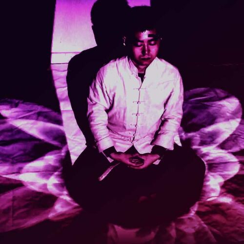 A person meditating cross-legged with a serene expression, surrounded by beautiful purple light patterns.